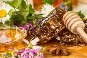 Organic raw honey with honeycomb, honey dipper and natural flowers